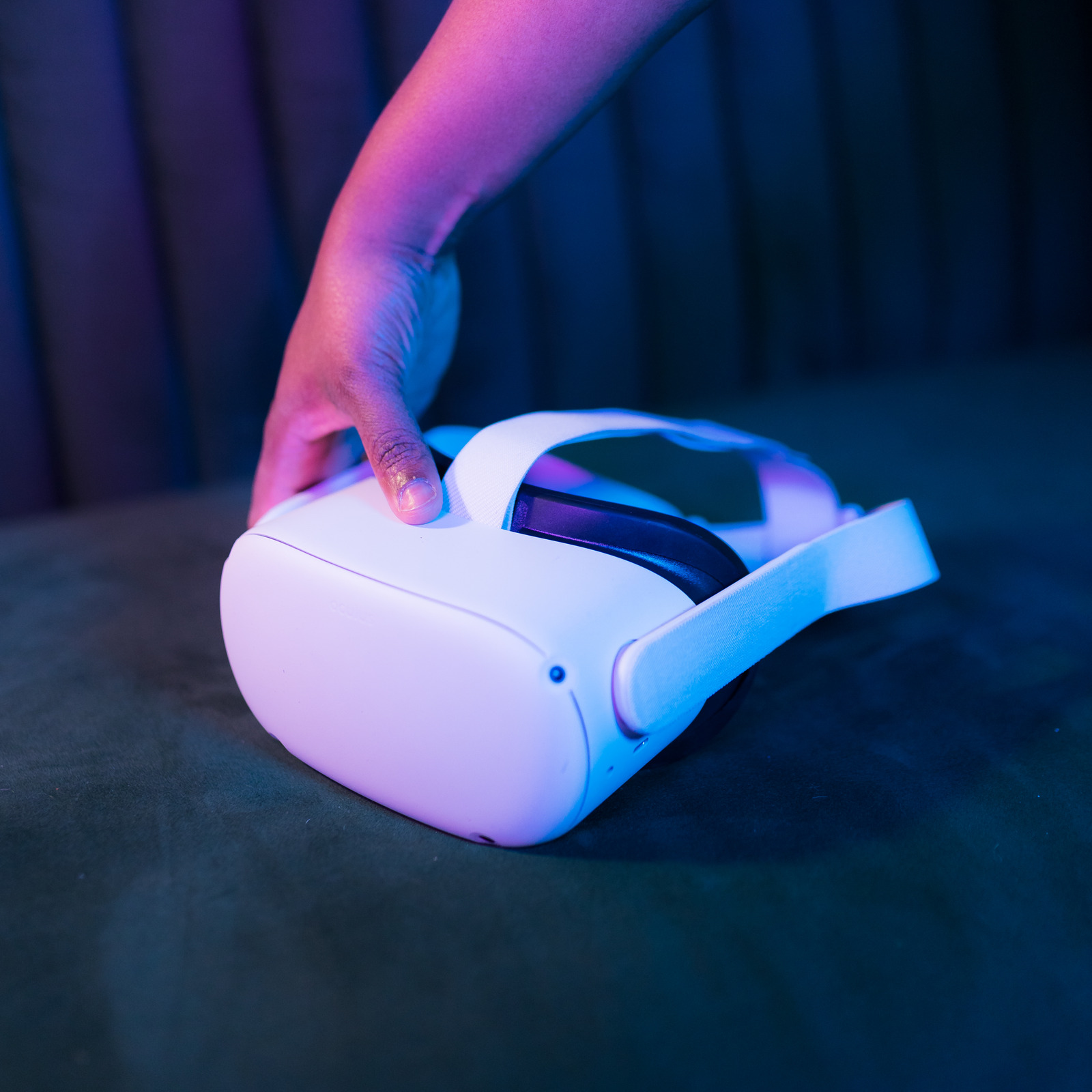 Une main attrape un casque de réalité virtuelle posé sur une table.