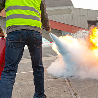 Personne en formation utilisant un extincteur pour éteindre un feu